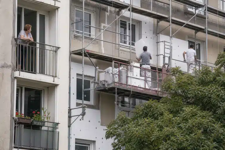 Ouvrier sur échafaudage peignant façade d'immeuble