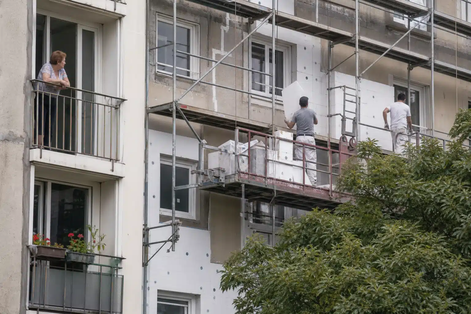 Ouvrier sur échafaudage peignant façade d'immeuble